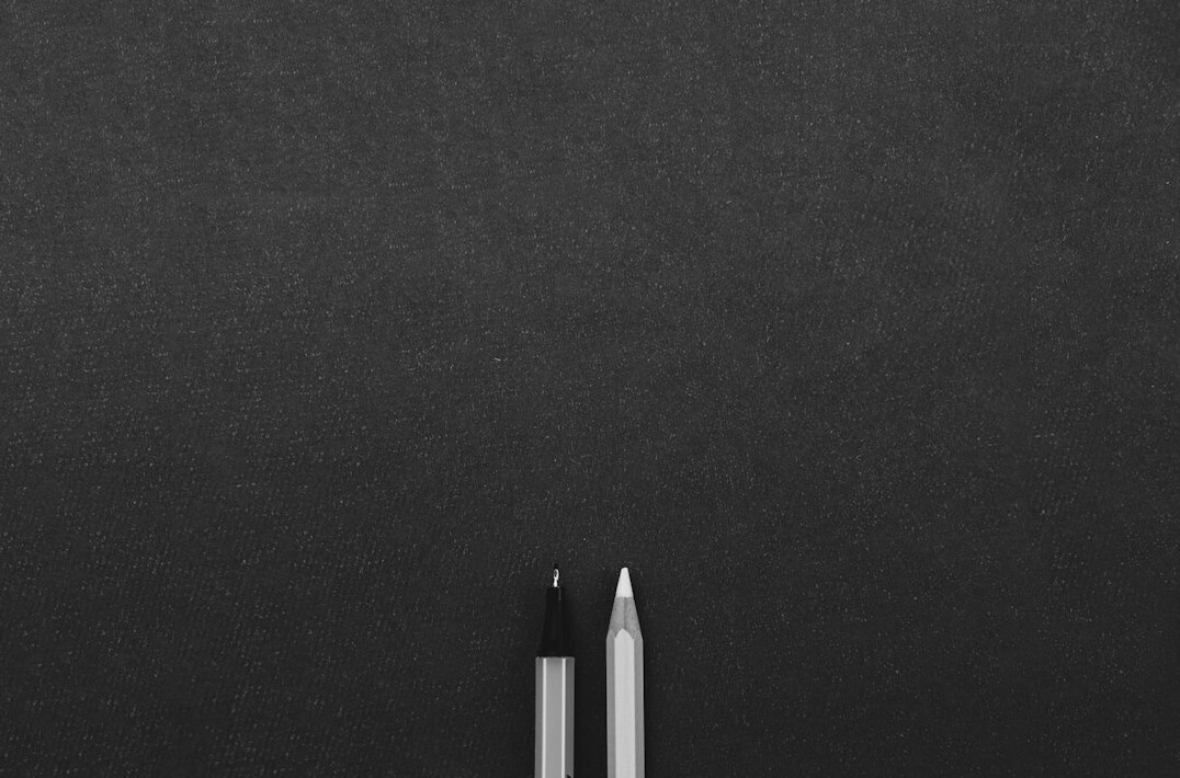 Writing content in a notebook next to a laptop